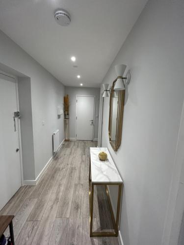 a living room with a table and a hallway at Stylish Meets Luxury! 2 Bed 2 Bath Family Home in Dagenham