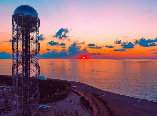 a tower on the beach with a sunset in the background at Batumi Orbi Super Apartments in Batumi