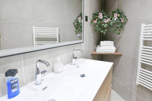 La salle de bains est pourvue d'un lavabo, d'un miroir et de fleurs. dans l'établissement Suites Sacré-Cœur Basilica, à Paris