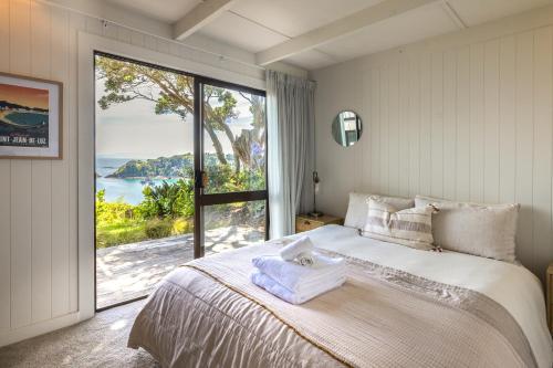 a bedroom with a large bed with a large window at Clifftop Sanctuary in Oneroa