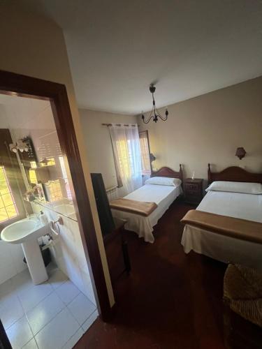 sypialnia z 2 łóżkami, umywalką i lustrem w obiekcie Hostal Sabor Fusion w mieście La Pradera de Navalhorno
