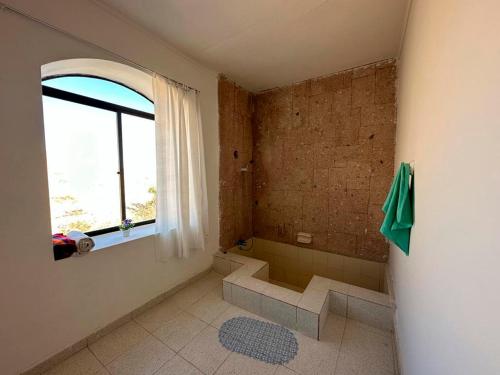 a bathroom with a shower and a sink and a window at Hotel Termas del Salitre in Mamiña