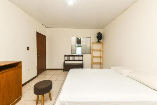a bedroom with a white bed and a chair at Rental Florianópolis - Acomodações Residenciais in Florianópolis