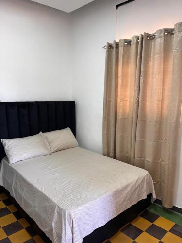 a bedroom with a bed with a black headboard and curtains at APARTAMENTO ZONA COLONIAL R in Santo Domingo