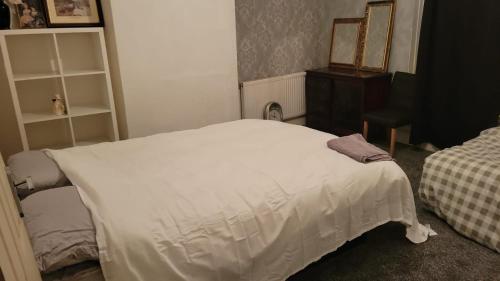 ein Schlafzimmer mit einem weißen Bett und einer Kommode in der Unterkunft 234 Belgrave in Oldham