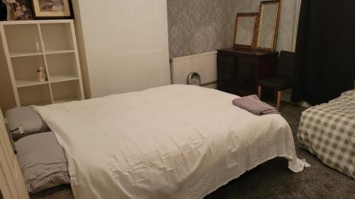 a bedroom with a white bed and a dresser at 234 Belgrave in Oldham