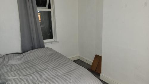 Bett in einem Zimmer mit Fenster in der Unterkunft 234 Belgrave in Oldham