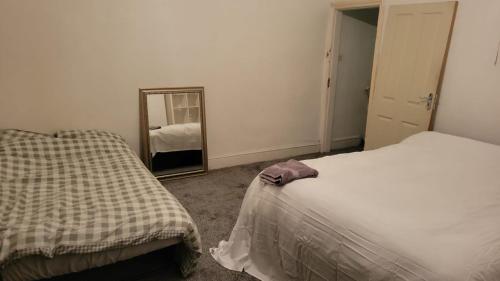 a bedroom with two beds and a mirror at 234 Belgrave in Oldham
