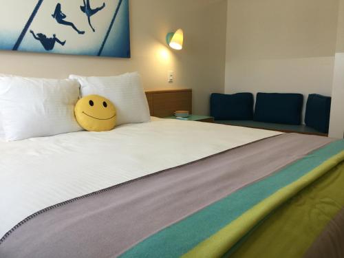 a bed with a smiley face pillow on it at The Beverly Laurel Hotel at West Hollywood in Los Angeles