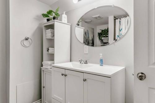 ein weißes Badezimmer mit einem Waschbecken und einem Spiegel in der Unterkunft Lakeside Retreat near Toronto in Mississauga