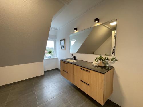 a bathroom with a sink and a mirror at aday - Frederikshavn Penthouse in Frederikshavn