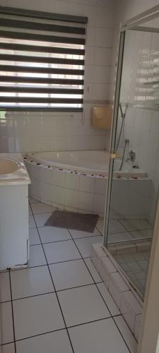 a bathroom with a tub and a glass shower at Matina Guest House in Johannesburg