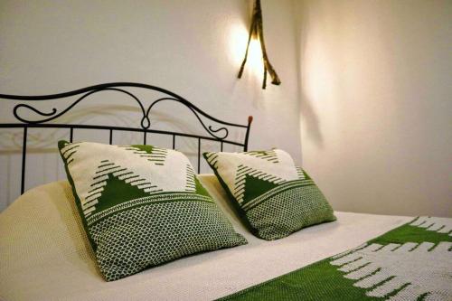 Una cama con dos almohadas verdes y blancas. en Sopas e Descanso en Grândola