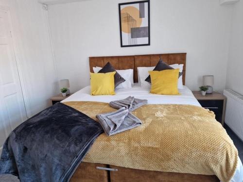 a bedroom with a large bed with yellow pillows at Cosy 3 Bedroom House in Beeston, Leeds, LS11 7JP in Beeston