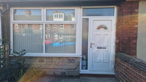 a white door on a brick house with a window at Cosy 3 Bedroom House in Beeston, Leeds, LS11 7JP in Beeston