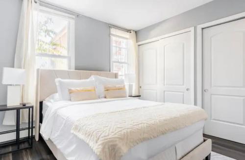 een witte slaapkamer met een groot wit bed en ramen bij Cozy House 20 min to NYC up to 8 People in Fairview