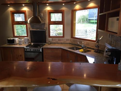 cocina con fregadero, fogones y ventanas en Casa Las Rosas, en San Carlos de Bariloche