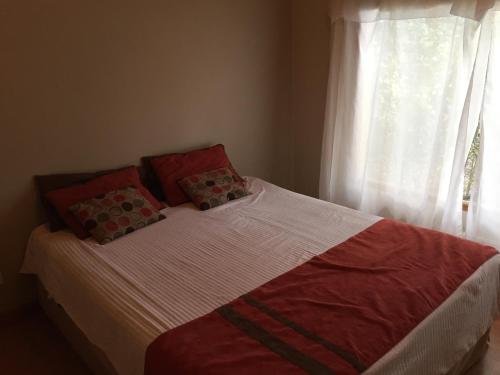 1 cama con 2 almohadas y ventana en Casa Las Rosas en San Carlos de Bariloche