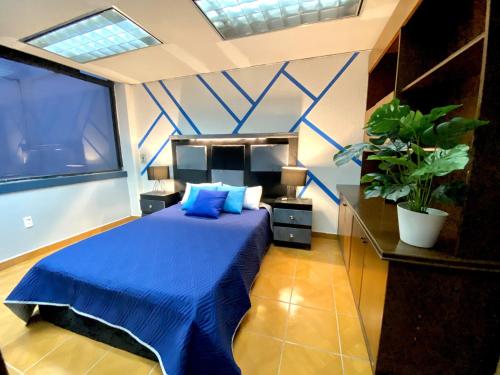a bedroom with a blue bed and a large window at ROOMIES HOSTEL Cibeles in Mexico City