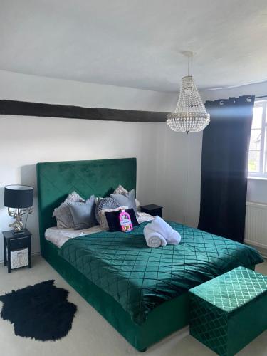 a bedroom with a green bed and a chandelier at The Farm Rooms in Stapleford Tawney