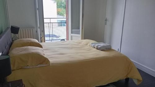 a bedroom with a yellow bed with two towels on it at Cassiopée avec jardin in Fleury-les-Aubrais