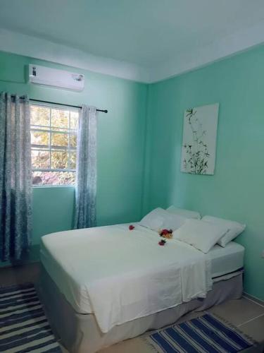 a blue bedroom with a white bed with a window at The Ultimate Escape in Soufrière