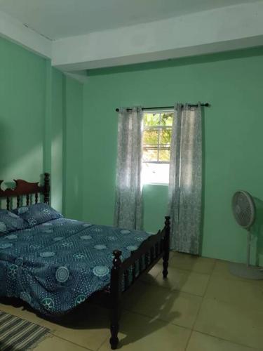a blue bedroom with a bed and a window at The Ultimate Escape in Soufrière