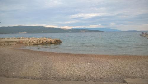 a beach with a group of rocks in the water at Apartmani Adrijan Krk in Krk