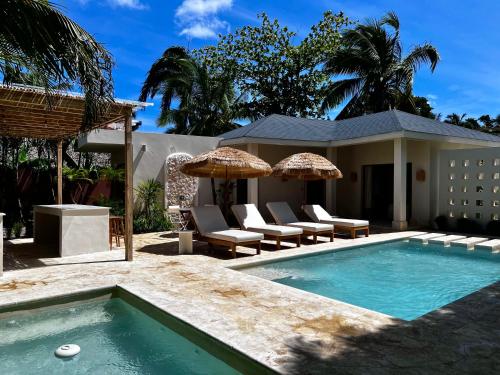 uma piscina com cadeiras e guarda-sóis ao lado de uma casa em Kaikai Beach House, un lujo en el Caribe em Las Terrenas