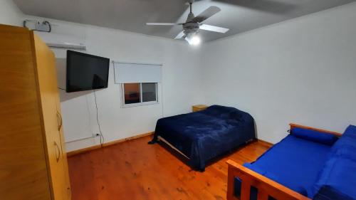 1 dormitorio con 1 cama azul y TV de pantalla plana en Caribe en Concepción del Uruguay