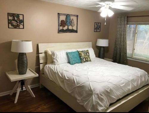 ein Schlafzimmer mit einem Bett mit weißer Bettwäsche und zwei Lampen in der Unterkunft Carl Nespoli in Fayetteville