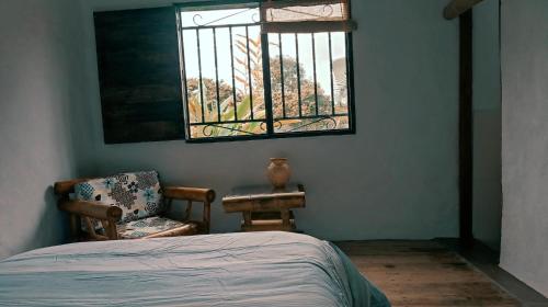 sypialnia z łóżkiem, krzesłem i oknem w obiekcie Pinar del Rio Eco Habitación Madera w mieście San Agustín