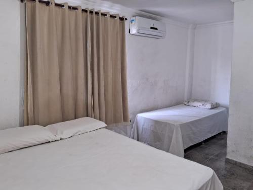 a room with two beds and a window with curtains at Hotel Raiz in Manaus