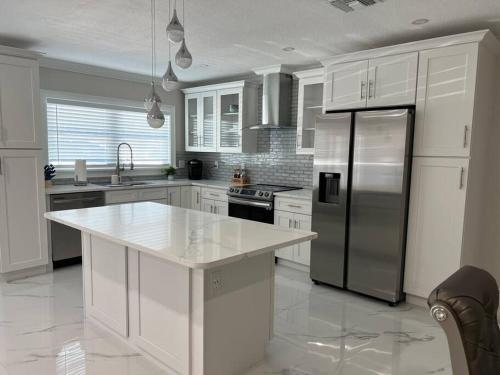una cucina con armadi bianchi e frigorifero in acciaio inossidabile di Charming Luxury House a Largo