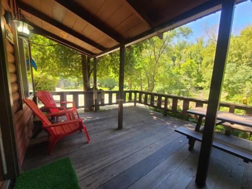 a porch with two red chairs and a picnic table at Fern River Resort in Felton