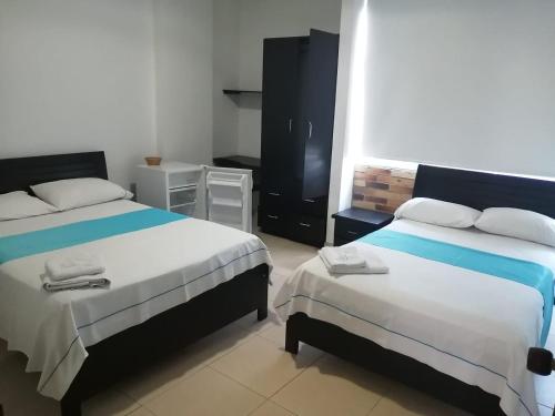 a hotel room with two beds and a small room at Hotel Canacabare Plaza in Yopal
