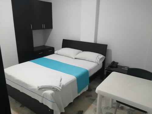 a bedroom with two beds and a table and a desk at Hotel Canacabare Plaza in Yopal