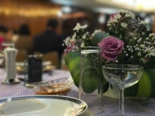 a table with two wine glasses and a vase of flowers at Hotel D´ Alba in Río Blanco