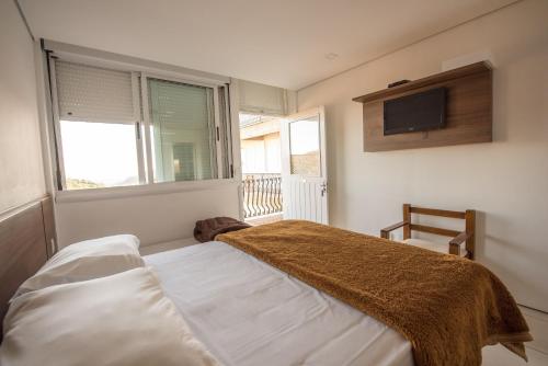 een slaapkamer met een bed en een tv aan de muur bij Hotel Villa Deifiori in Bento Gonçalves