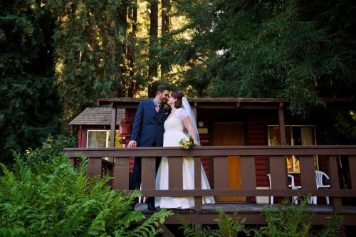 a bride and groom standing on a bridge at Fern River Resort in Felton