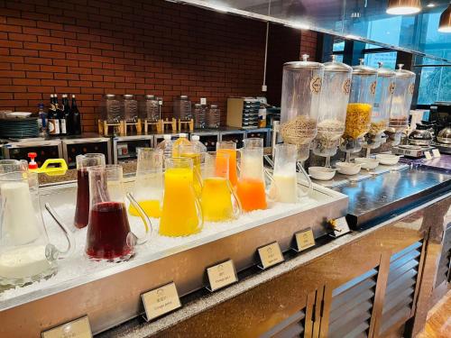 a counter with many glass vases with different colored liquids at City Hotel Xiamen-Free Welcome Fruits in Xiamen