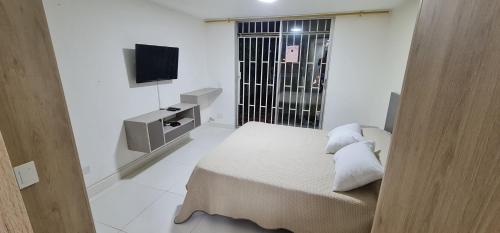 a small white room with a bed and a television at Hermosa casa en Medellin. Cerca a estación del metro in Medellín