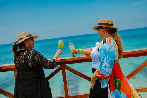 two women standing at a bar on the beach holding drinks at Solarium Beach Club in Playa Blanca