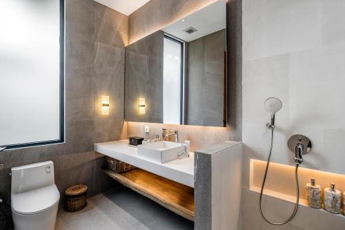 ein Badezimmer mit Waschbecken, Toilette und Spiegel in der Unterkunft Priviere Luxury Villa - Canggu in Canggu