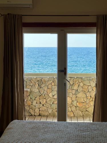 a bedroom with a view of the ocean through doors at Lands End in West End