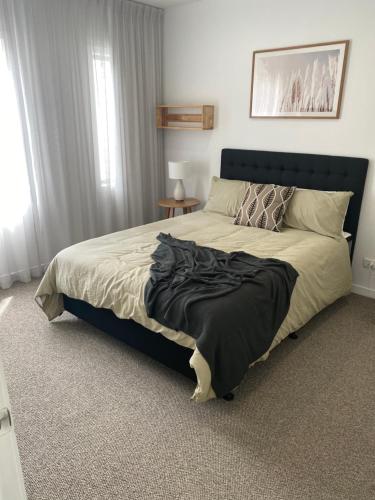 een slaapkamer met een groot bed met een zwart hoofdeinde bij Waterfront 209 in Paihia