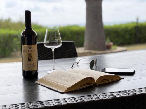 una bottiglia di vino e un libro aperto su un tavolo di Holiday home in Costa Rei 22891 a Costa Rei