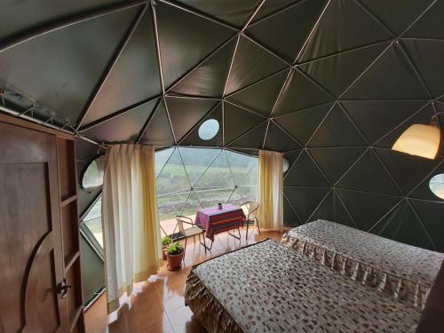 a bedroom with two beds and a large window at Sky Lodge Domes Salkantay in Soray