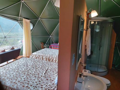 y baño con cama, ducha y lavabo. en Sky Lodge Domes Salkantay, en Soray