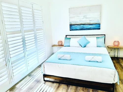 a bedroom with a large bed with blue pillows at Surfside Holiday Home 100m Beach in Batemans Bay